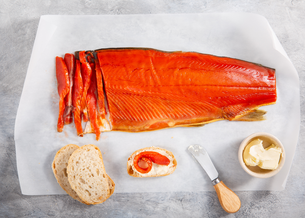 Smoked salmon fillet with bread and cream cheese on a marble surface.