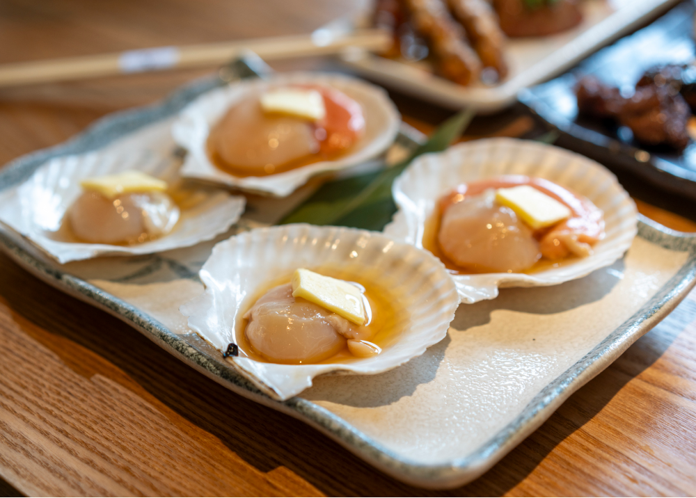 Grilled scallops served in shells with lemon wedges.